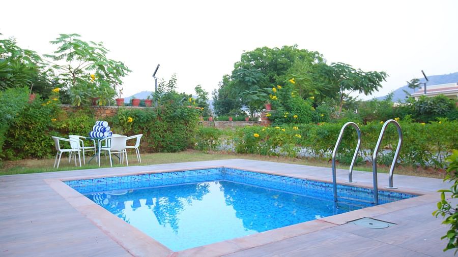 Outdoor swimming pool in front of the villa, with an open top to the clear sky and chairs arranged infront