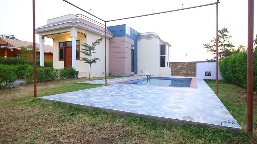 Facade of the Party Villa with Pool at Aanandam Resort & Spa, featuring plants lining the pathway and a swimming pool beside the building