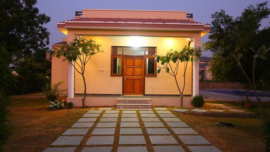 Exterior view of the Family Party Villa with Pool at Aanandam Resort & Spa, beautifully illuminated by warm light against the backdrop of a vibrant sunset sky