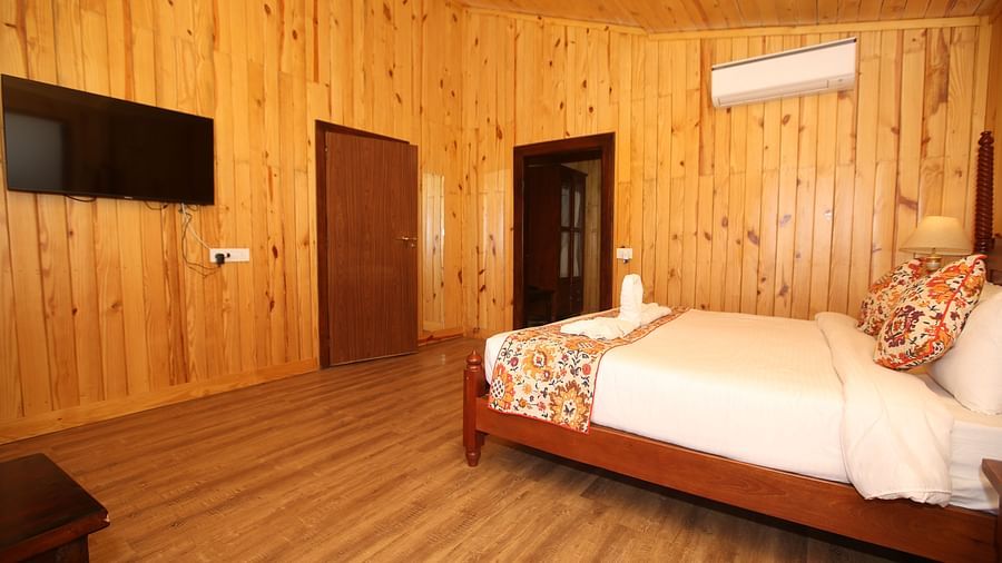 Spacious Kashmir Cottage Villa's Pool room with a king-sized bed, wooden flooring, and a wall-mounted TV at Aanandam Resort & Spa