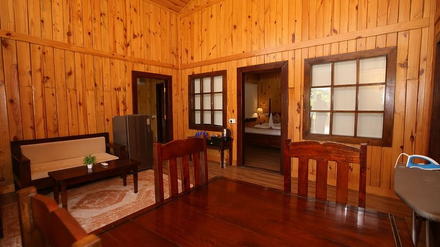 Cozy corner seating in Kashmir Cottage Villa's Pool room, featuring a sofa, chair, and stylish wooden flooring at Aanandam Resort & Spa