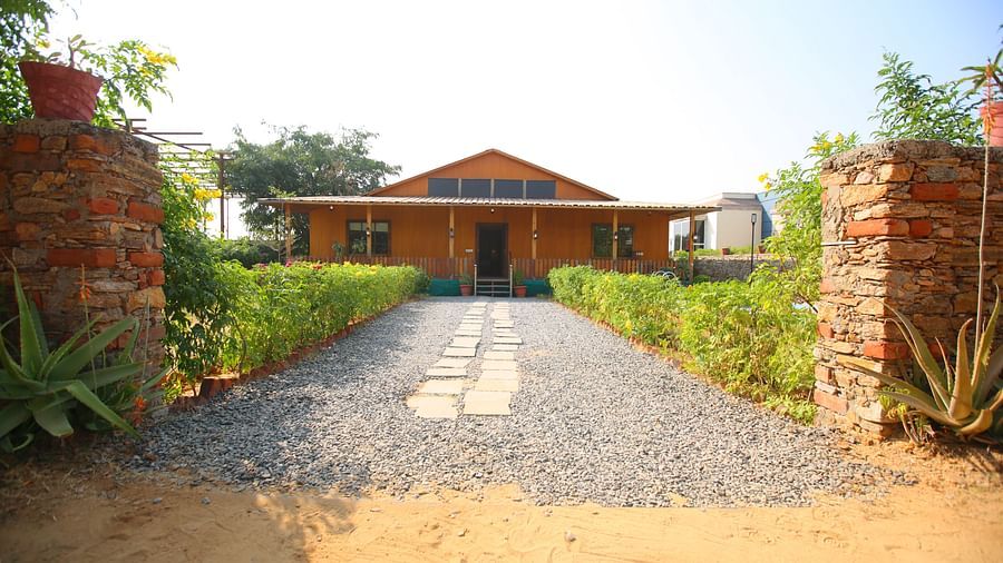 Facade of Kashmir Cottage Villa's Pool room with a pathway adorned with plants at Aanandam Resort & Spa