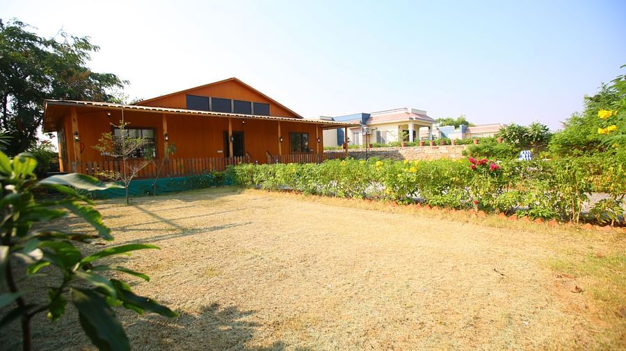 Side view of the facade of Kashmir Cottage Villa's Pool room, surrounded by greenery at Aanandam Resort & Spa