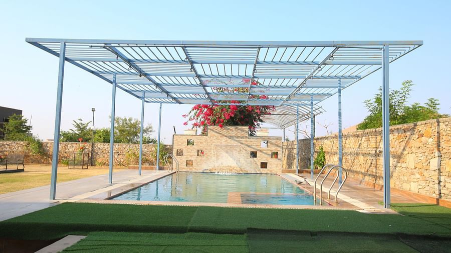Open terrace swimming pool at Aanandam Resort & Spa, featuring Bougainvillea plants in the background and a serene view of the clear sky