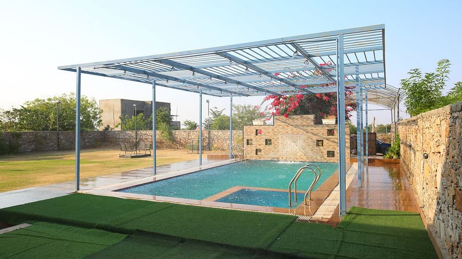 Open terrace swimming pool at Aanandam Resort & Spa, featuring Bougainvillea plants in the background and a serene view of the clear sky