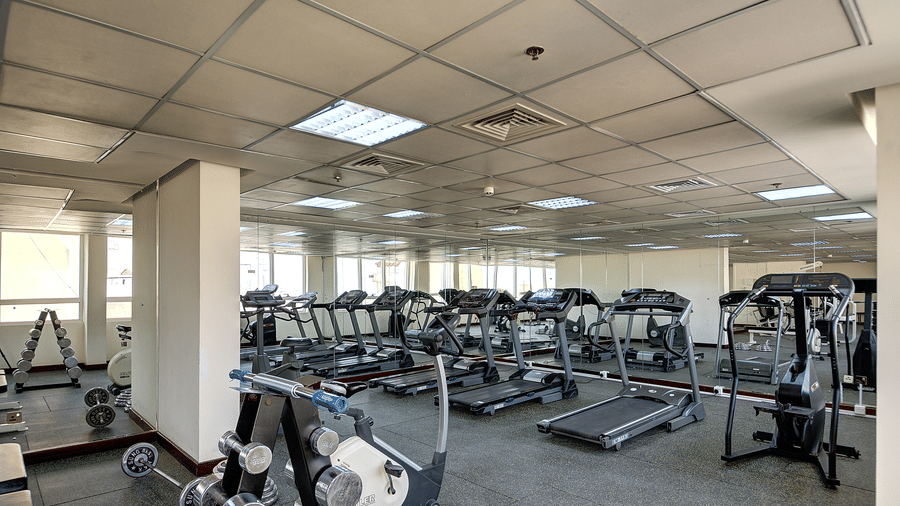 A spacious gym area with various weight machines and resistance equipment under bright lights - Al Manar Grand Hotel Apartment, Bur Dubai