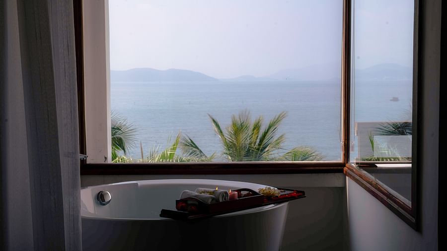 A bathtub in a room near a window over looking the view of the sea - Alibu Resort Nha trang