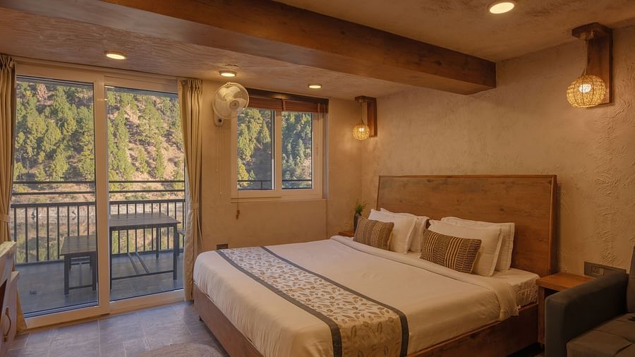 Room with double bed, balcony doors, wooden beams on the ceiling, and soft lighting.