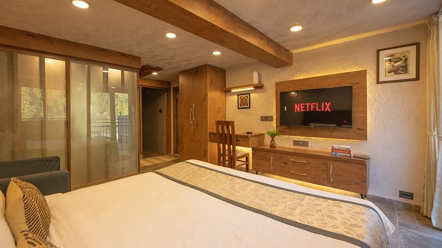 Room with double bed, TV, balcony doors, wooden beams on the ceiling, and soft lighting.