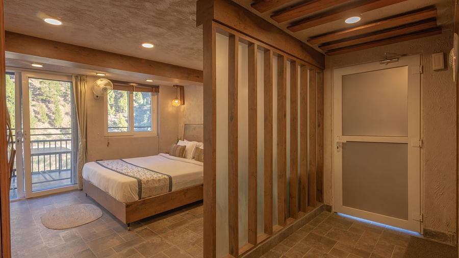 Room with double bed, balcony doors, wooden beams on the ceiling, and soft lighting.