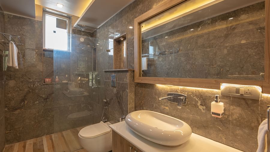 Clean bathroom with a white toilet, sink, vanity mirror, bidet sprayer, and small window, set against light walls