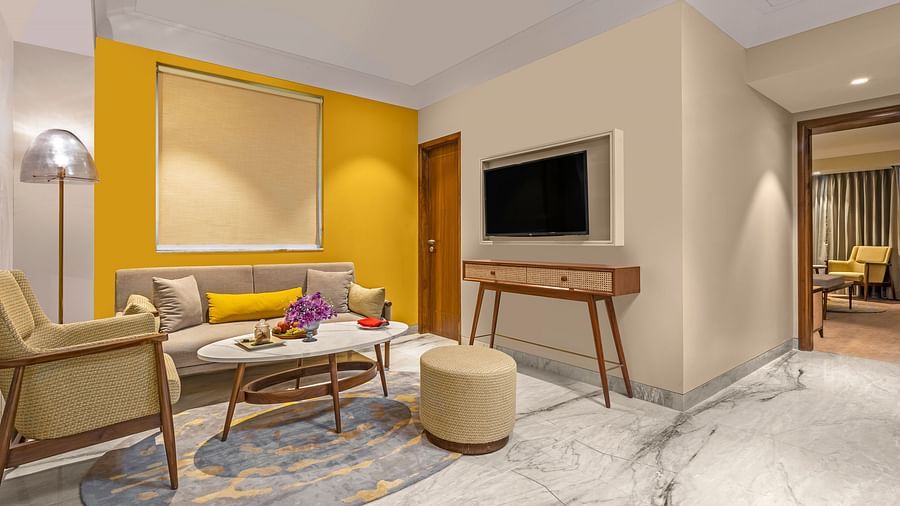 An image of a living room featuring a comfortable sofa, a coffee table, a television mounted on the wall.