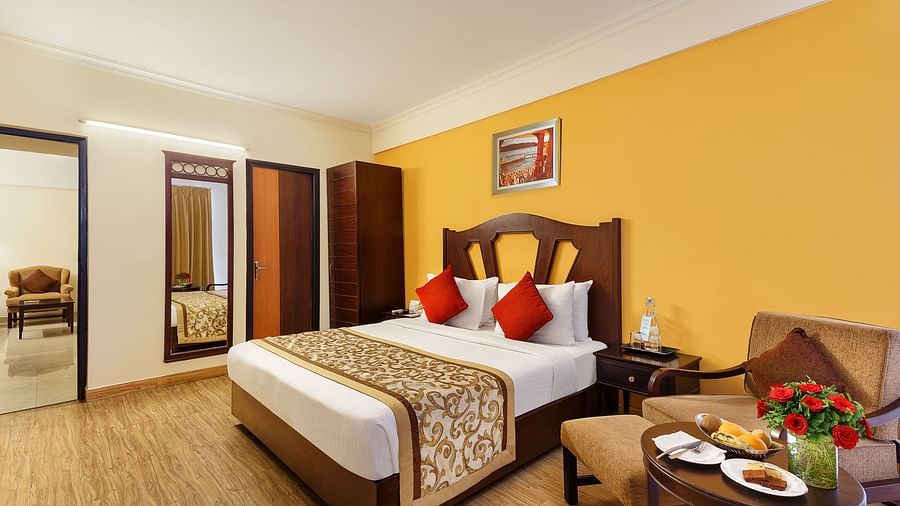 A side angle image of the room featuring a king size bed, coffee table and a wall painting hanging on the wall an d a TV.