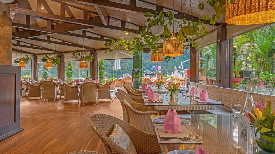 A spacious restaurant with a wooden floor and exposed wooden beams on the ceiling. Large windows offer views of the outdoors.