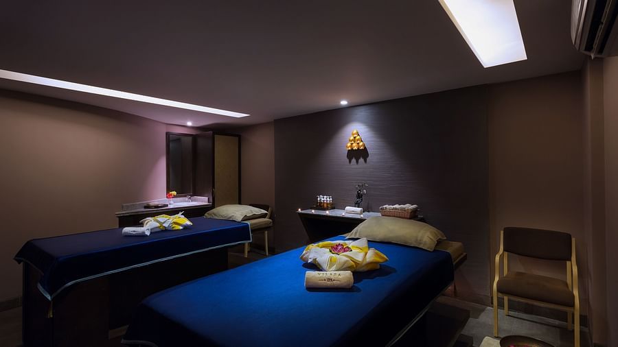 A relaxing room with two single beds covered in sheets. 