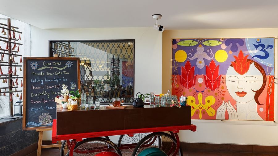 A colourful and vibrant interior with a red cart. A large painting hangs on the wall behind.
