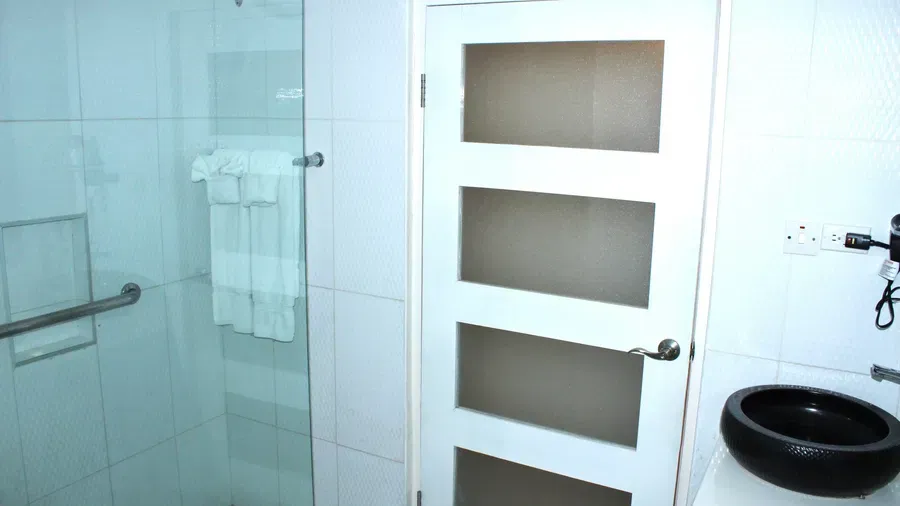 A bathroom with a clear glass shower enclosure and a separate toilet area, featuring a modern design | Executive King Room | Altamont Court, Jamaica