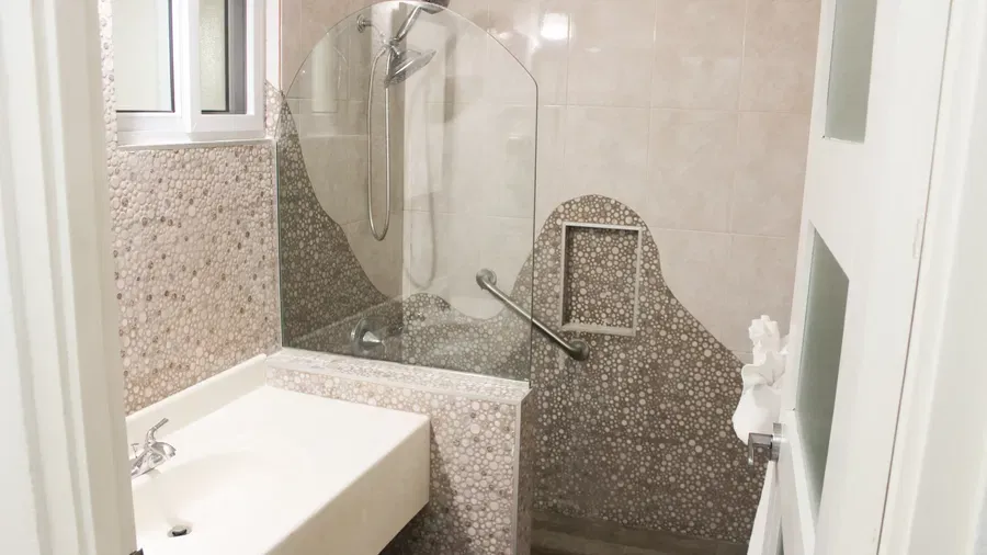 A modern bathroom features a shower stall with a glass door, a toilet, and a vanity with a sink | Executive King Room | Altamont Court, Jamaica