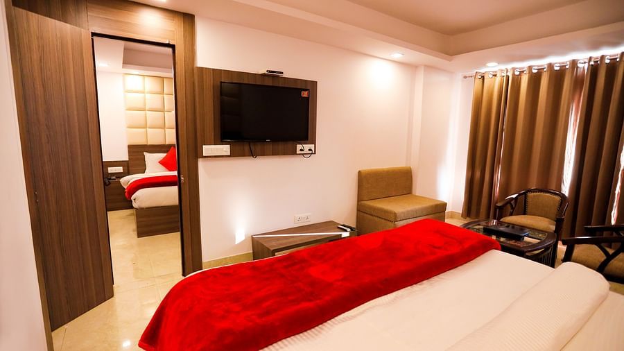 Image of a room with a bed and a door in front connecting to the next room in front at Amara Hill Queen, Mussoorie.