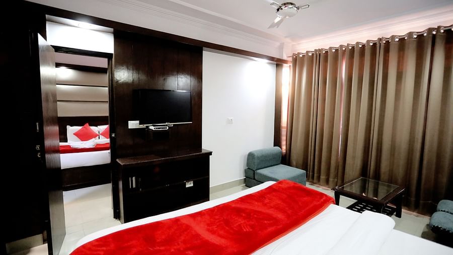 Image of a room with a bed and a door leading to another room with a bed at Amara Hill Queen, Mussoorie.