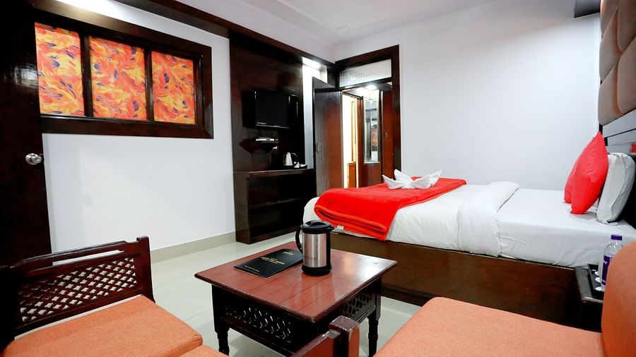 Side view of a room with a bed and a seating area with sofas on the side at Amara Hill Queen, Mussoorie.