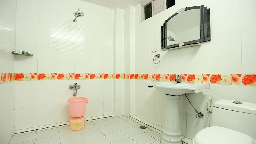 Image of a washroom with a toilet and a sink with a mirror above it at Amara Hill Queen, Mussoorie.