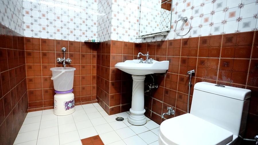 Image of a washroom with a toilet, a sink and a bucket at Amara Hill Queen, Mussoorie.