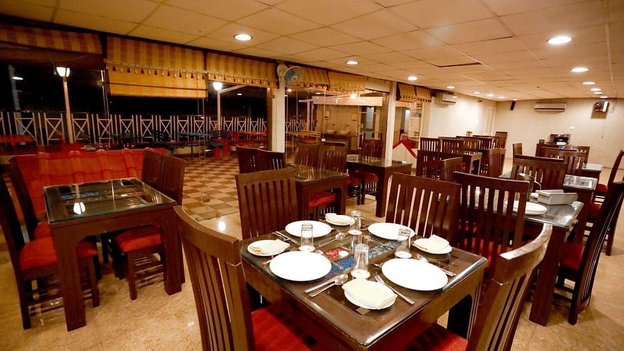 Image of a dining hall with tables and chairs with crockery placed on the table at Amara Hill Queen, Mussoorie.