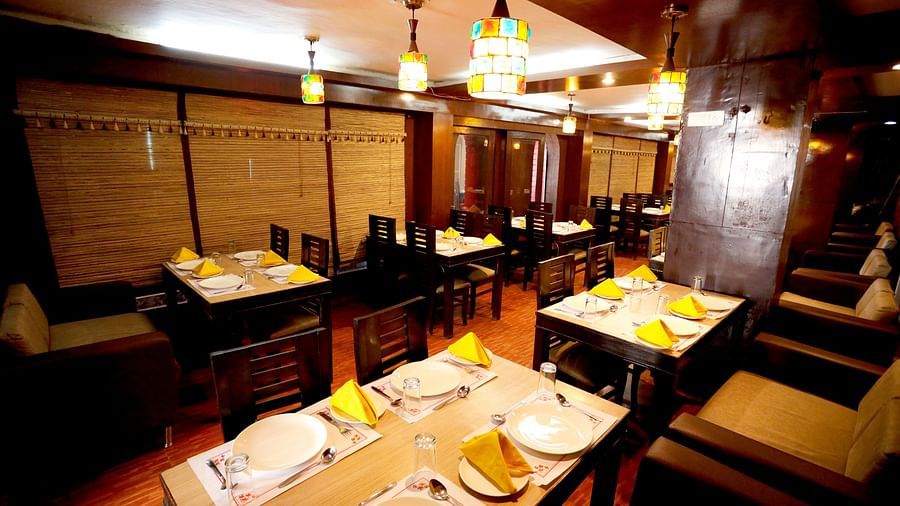 Image of a restaurant with tables and chairs as well as lights hanging from the ceiling at Amara Hill Queen, Mussoorie.