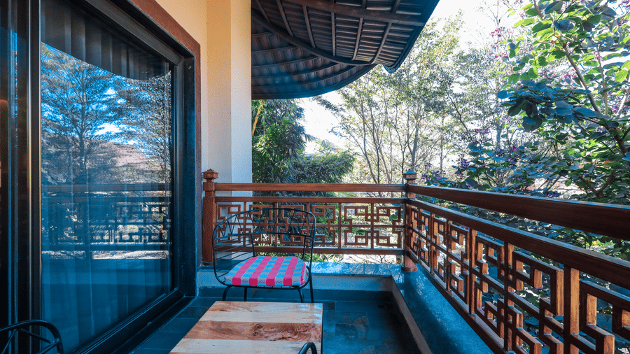 A balcony with seating facing outdoor trees and a railing at Ananta Spa & Resort, Jaipur.