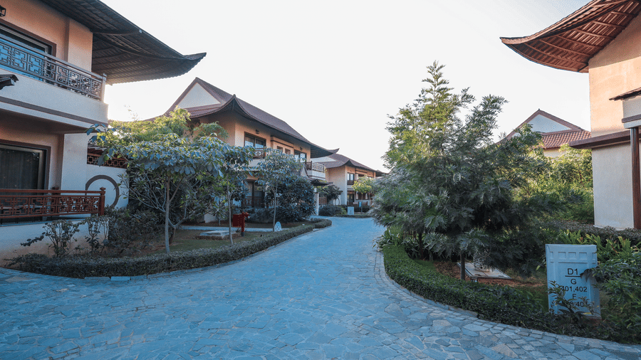 A courtyard path with buildings, plants and an open walkway at Ananta Spa and Resort, Jaipur