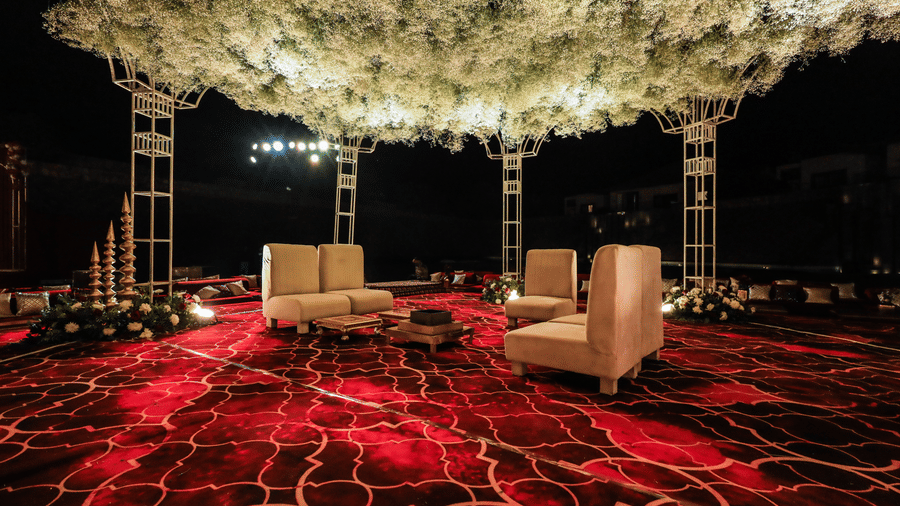 A seating arrangement under a floral overhead setup with chairs and tables at Ananta Spa and Resort, Jaipur