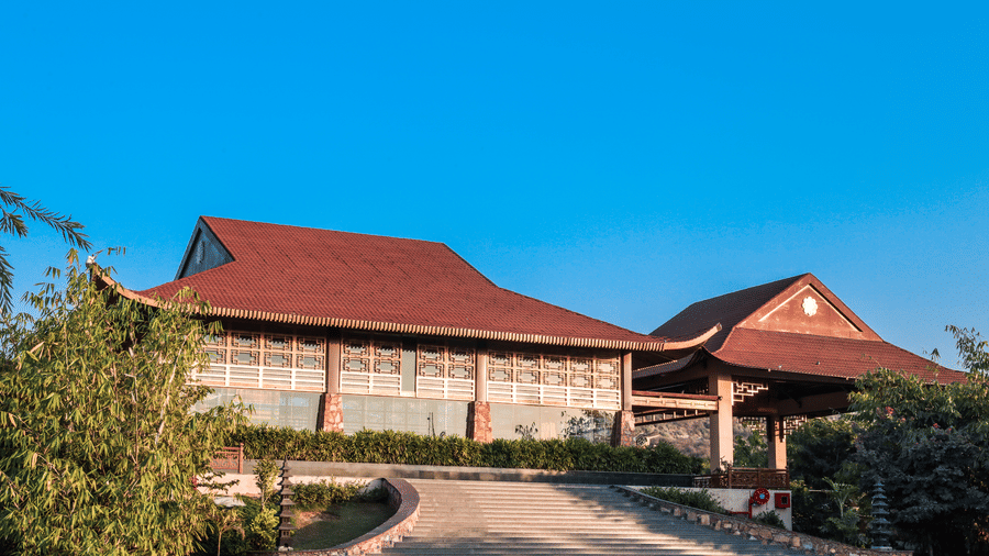 A garden front area with pathways, plants and a building in the background at Ananta Spa and Resort, Jaipur
