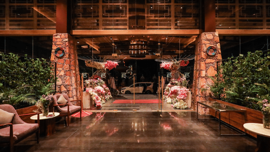 The interior entryway at Ananta Spa & Resort, Jaipur, features dark wooden floors, pink lounge chairs, and large pink floral decorations.