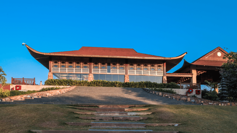 A main building view with open grounds, pathways and surrounding plants at Ananta Spa and Resort, Jaipur