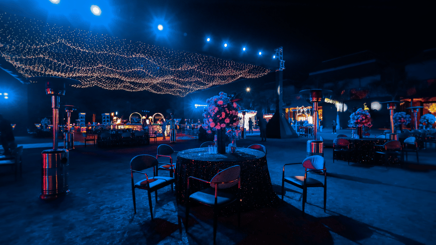 A wide outdoor event space at Ananta Spa & Resort, Jaipur, is beautifully lit at night with blue uplighting and canopy string lights.