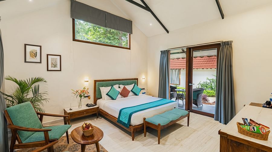 full view image from the corner of the luxury villa featuring a king size bed along with a full sized french windows at the far end of the room