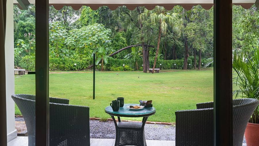 close up image of the private sit out area featuring a green laen with two arm chairs and a coffee table at the luxury family suite at aranya vilas in udaipur