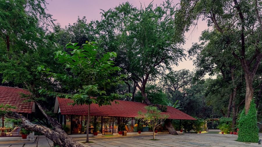 facade image of aranya vilas in a serene evening amidst lush greenery