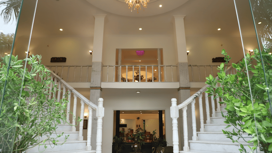 A staircase entrance with pillars and a chandelier at AS Hotels, Khajuraho.