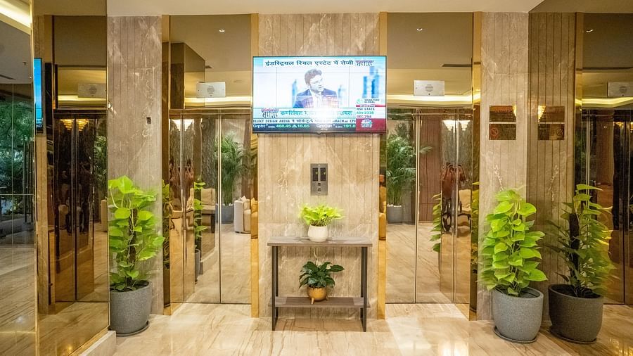 Lobby area of ASTER GRAND BY ZENQ SAKET with a TV, two lifts and lots of plants arranged.