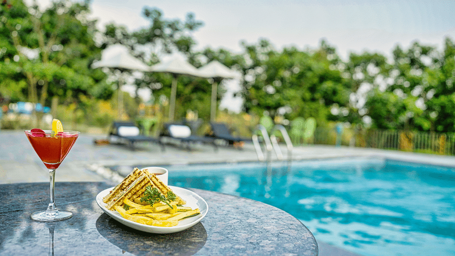 A picture with refreshing cocktail by the pool, with a snack platter and a beautiful view Atman, dharamshala