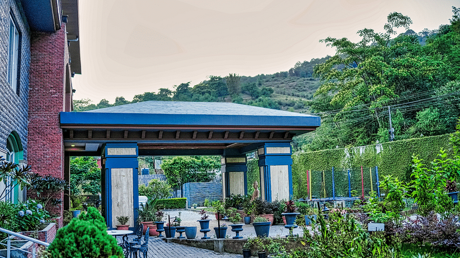A modern entrance with a spacious outdoor seating area and a scenic view - Atman Dharamshala.