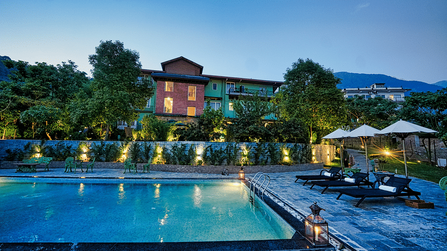 A picture with luxurious swimming pool, beautifully lit around and a scenic mountain view in the background - Atman, Dharamshala
