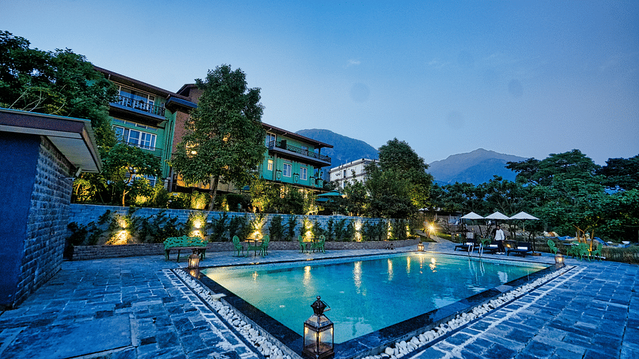 A picture with luxurious swimming pool, beautifully lit around and a scenic mountain view in the background - Atman, Dharamshala
