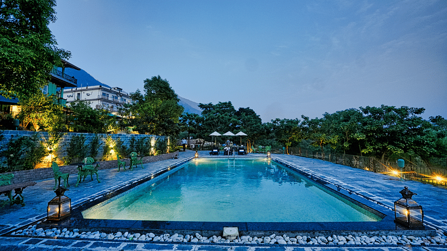 An image featuring swimming pool surrounded by trees, with a beautiful nature view in the background - Atman, dharamshala.
