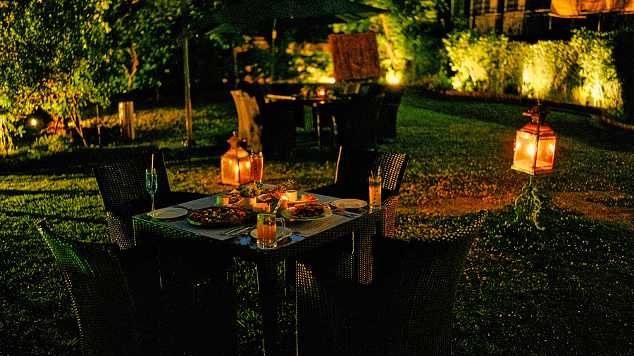 A picture of outdoor dining area with lanterns and string lights in the evening.
