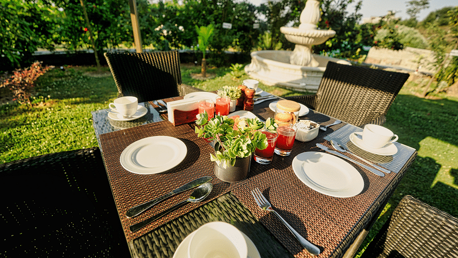 A picture of Outdoor breakfast setup with a table, chairs, and a beautiful garden view.