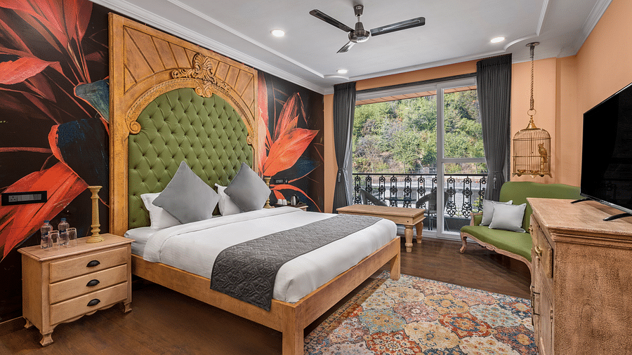 a bedroom with a wallpaper and a large green headrest and large windows leading out into the balcony - Atman, Dharamshala