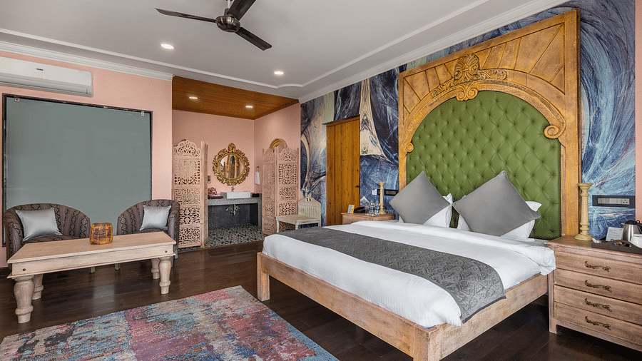a bedroom with a large double bed and two sofas with a table - Atman, Dharamshala